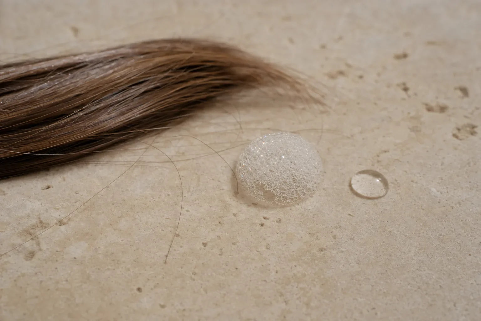 A dry lock with a lather bubble and droplet, best shampoo for dry hair.