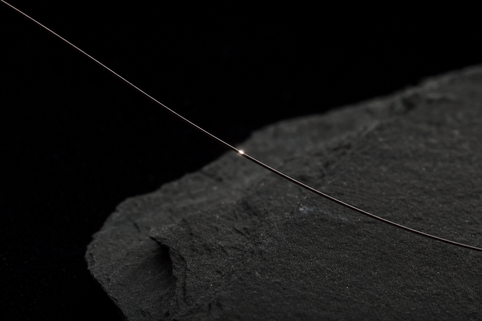 A single hair fibre catching a precise point of light, click chemistry for haircare.