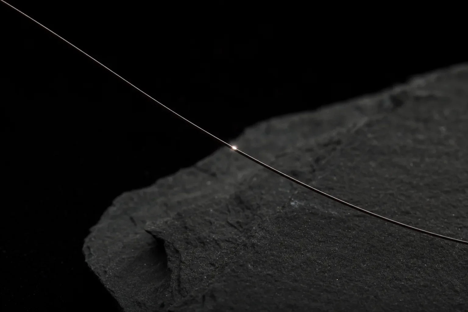 A single hair fibre catching a precise point of light, click chemistry for haircare.