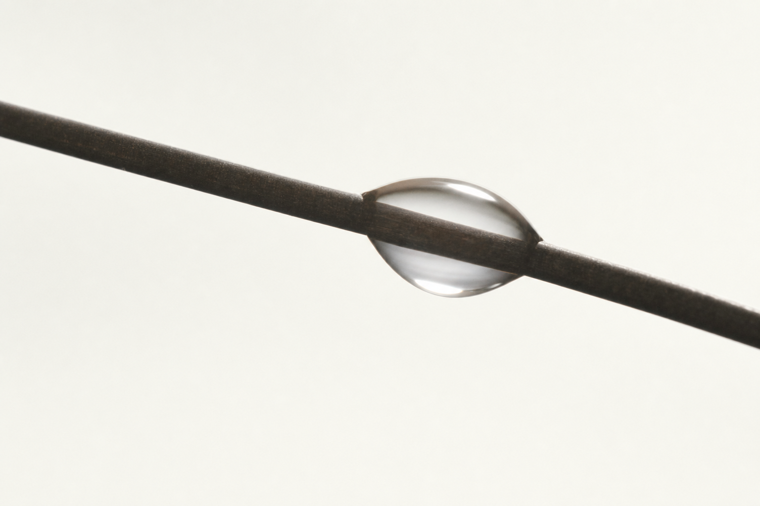 A water droplet wrapping a single sleek hair fibre, the 18-MEA layer.