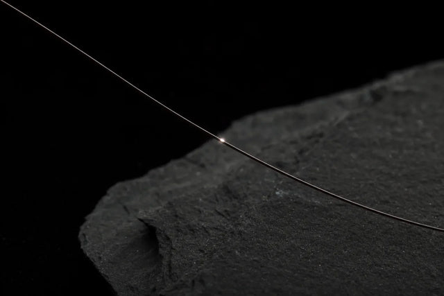 A single hair fibre catching a precise point of light, click chemistry for haircare.